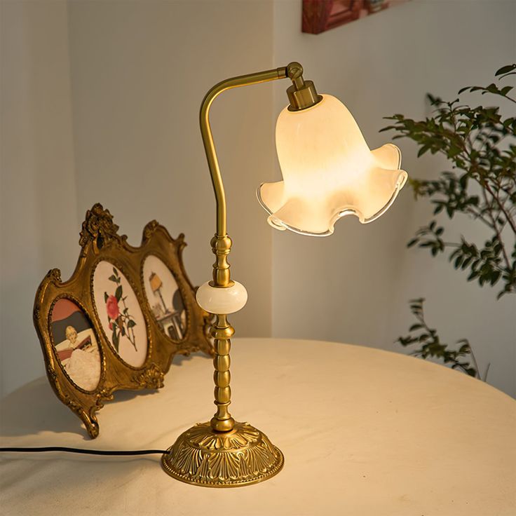 a table lamp sitting on top of a white table next to a clock and potted plant