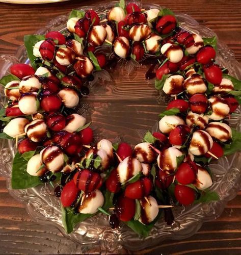 a cake that is sitting on a glass platter with fruit and leaves around it