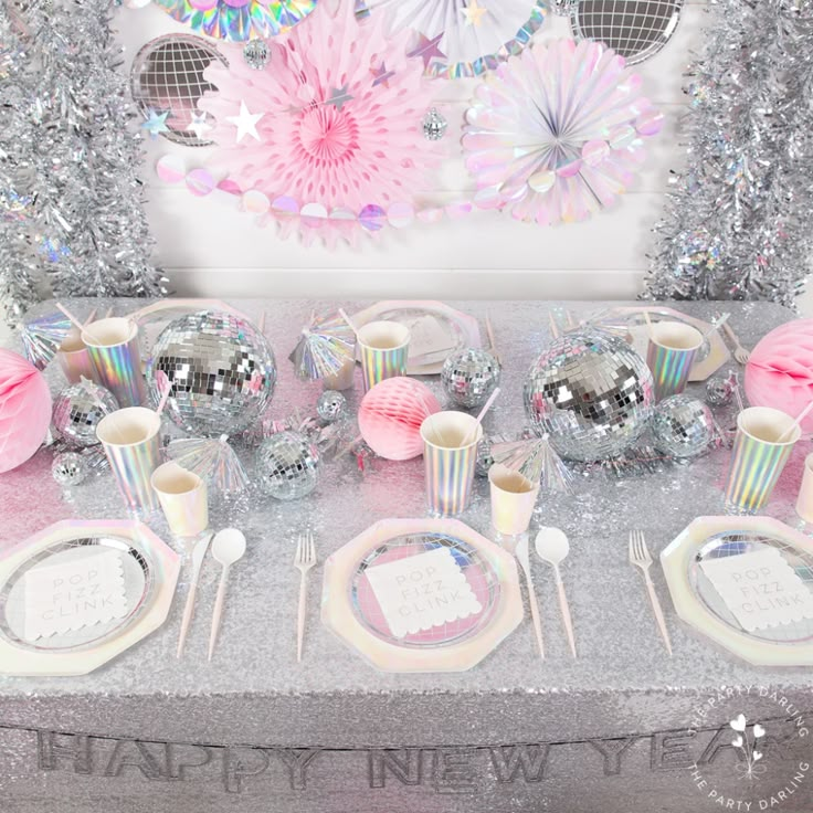 a table set up for a new year's eve party with pink and silver decorations