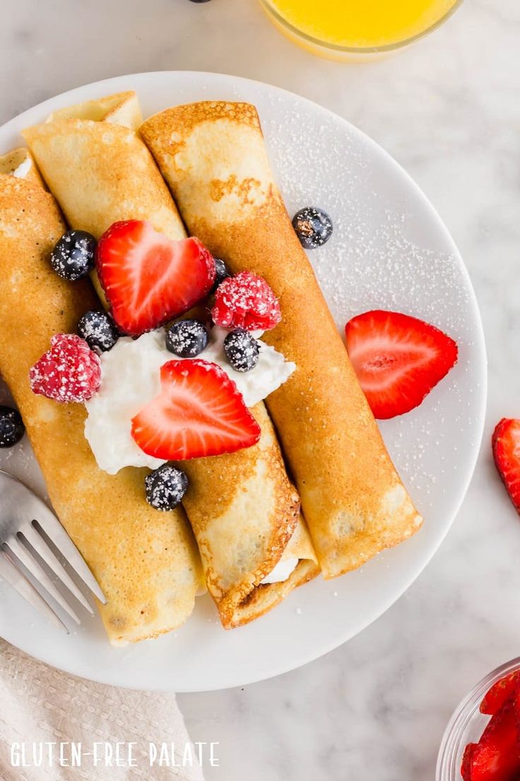 a white plate topped with crepes covered in fruit