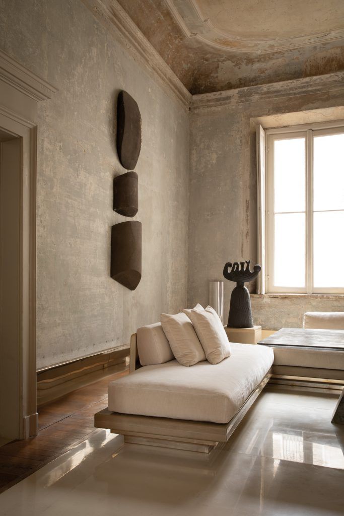 a living room with a couch, table and lamp on the wall next to a window