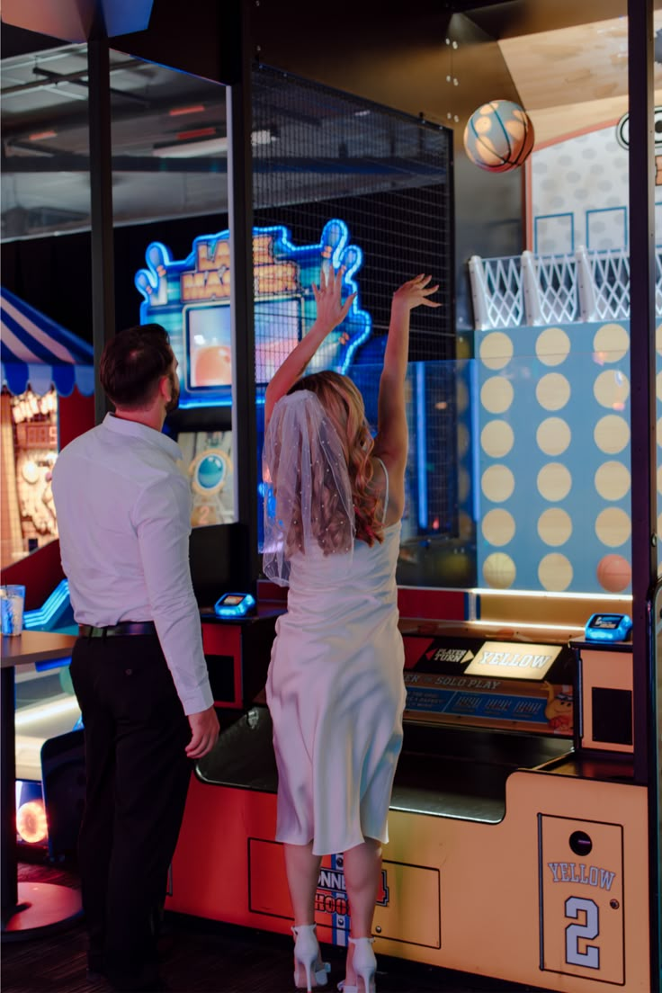 a man and woman standing in front of a machine with a basketball on it's back