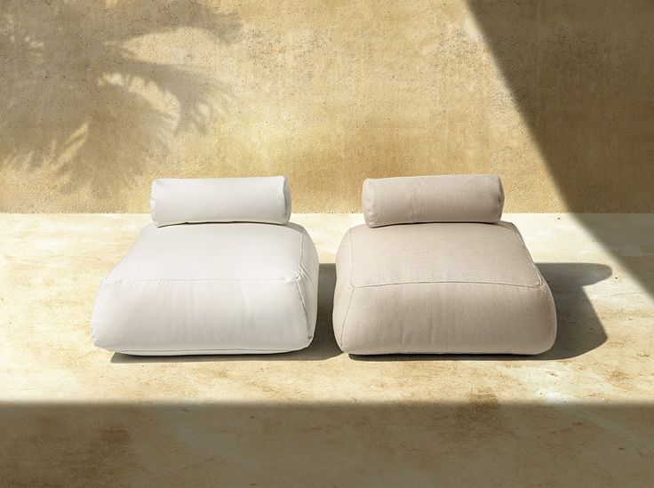 two pillows sitting next to each other on top of a cement floor near a wall