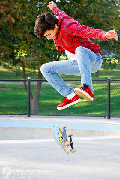 a young man is jumping in the air with his skateboard while wearing red sneakers