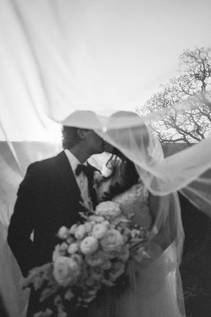 a bride and groom kissing under the veil