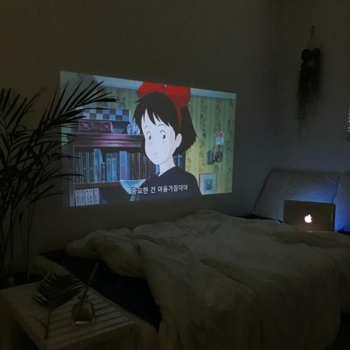 a room with a bed and a screen on the wall that shows an anime character