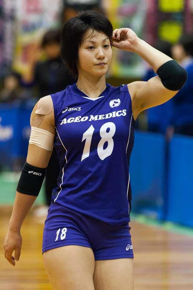 a female volleyball player is holding her hand up to her head while walking on the court