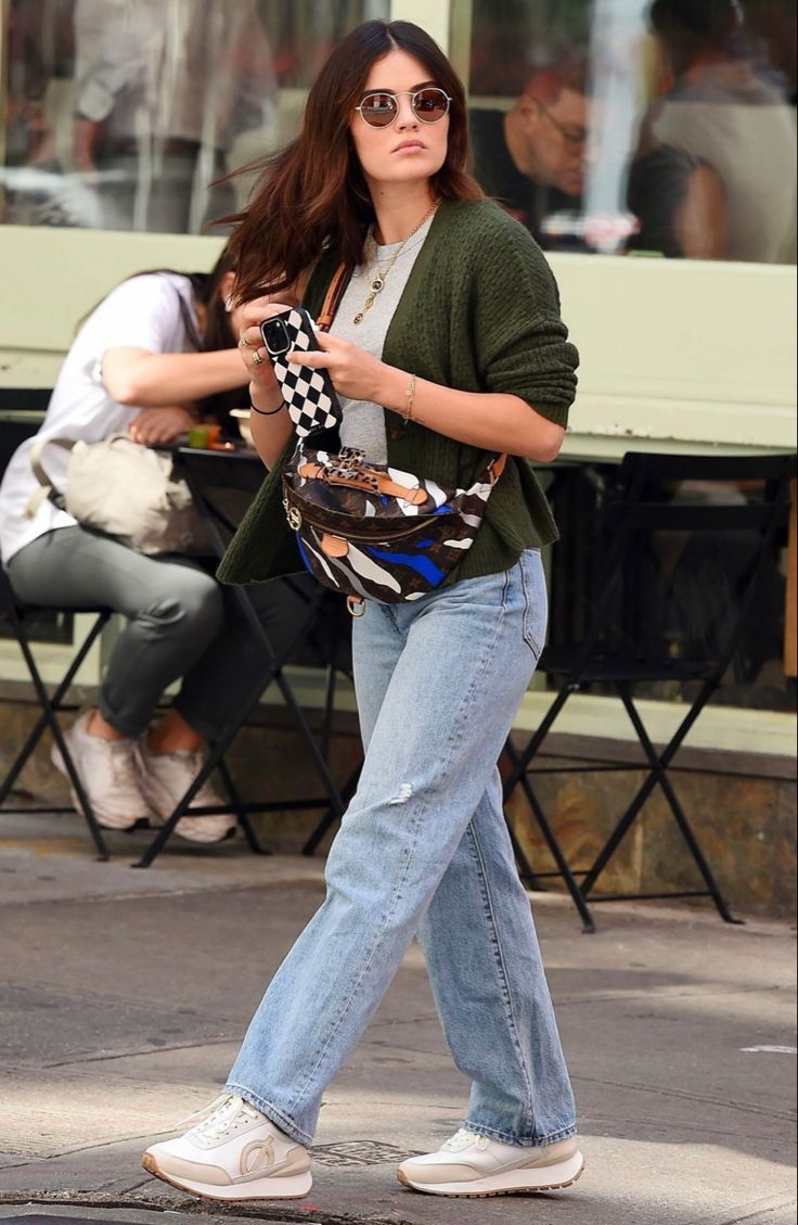 a woman is walking down the street while looking at her cell phone