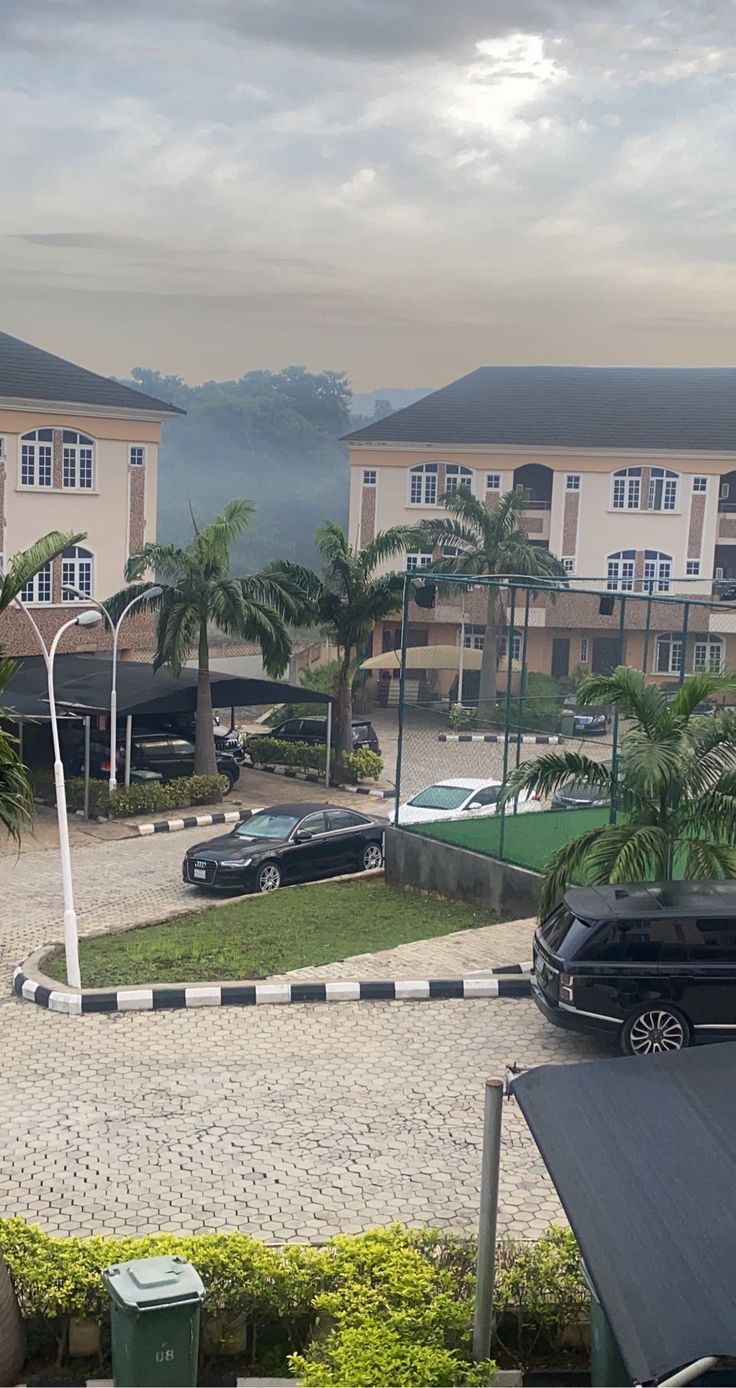 a black car is parked in front of some buildings and palm trees on the other side