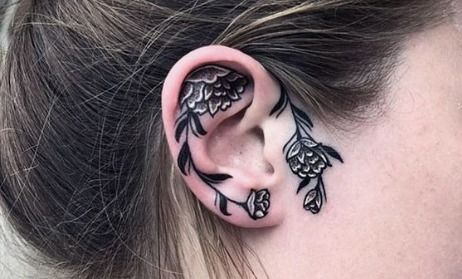 a woman's ear is decorated with black and white tattoos on her left side