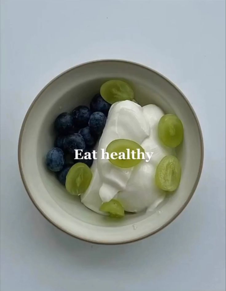 a white bowl filled with yogurt and grapes