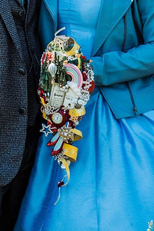 a man and woman dressed in blue standing next to each other holding a colorful bouquet