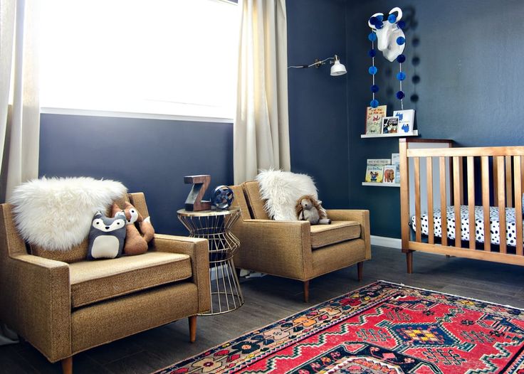 a baby's room with two chairs, a crib and a rug on the floor