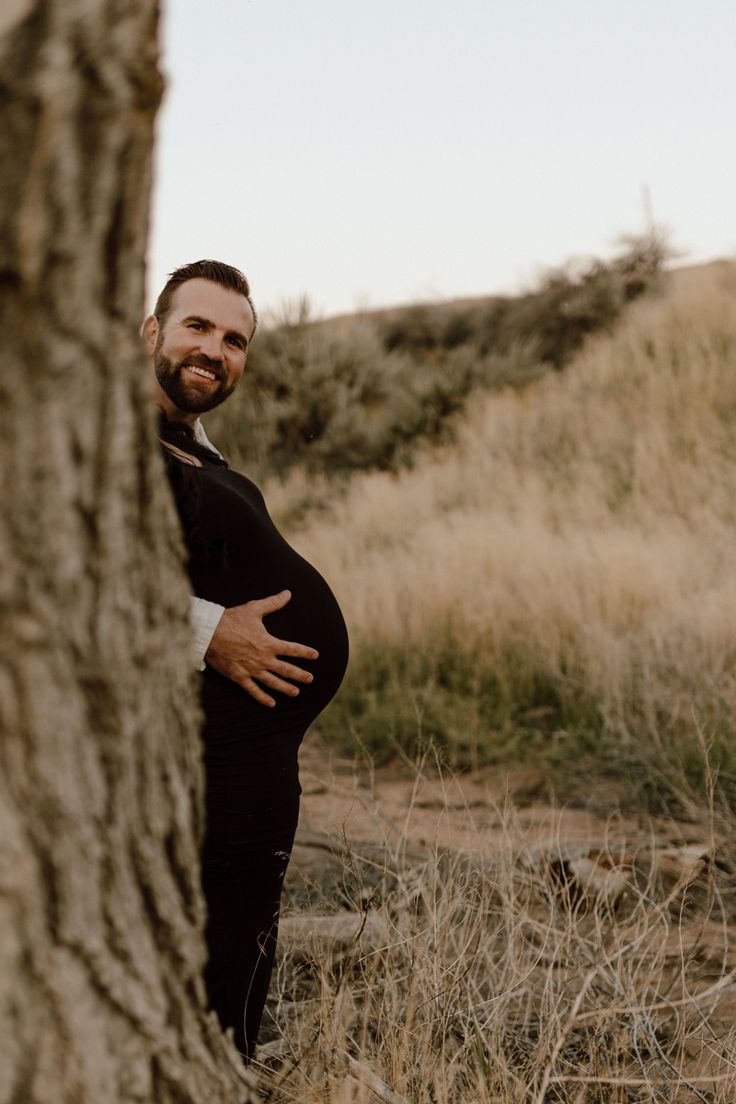 a man standing next to a tree with his belly wrapped around it's waist