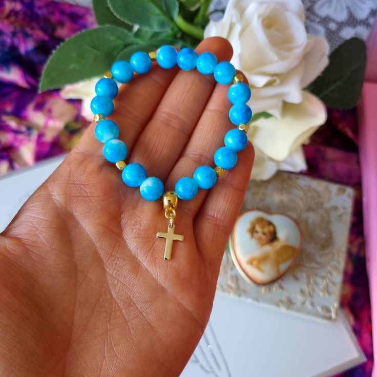 Super pretty blue beaded christian bracelet with a 18kt gold plated mini cross charm. This bracelet is made on super strong stretch cord and will fit most adults. It is really comfortable to wear and brightens up an outfit and can help you remember the LORD throughout the day with the reminder of the cross. Return to my shop : https://www.etsy.com/uk/shop/Sanctuswonders Thank you for visiting my shop! I hope you find what you are looking for! I specialise in and like to sell the following: Chris Turquoise Rosary Bracelet Gift, Turquoise Rosary Bracelet With Round Beads As Gift, Gold Cross Beaded Bracelets For Gift, Gold Beaded Rosary Bracelet With Cross Shape, Gold Cross-shaped Beaded Bracelets For Gifts, Gift Beaded Cross Rosary Bracelet, Beaded Cross Rosary Bracelet Gift, Beaded Cross Rosary Bracelet For Gift, Gold Cross Bracelet For Baptism