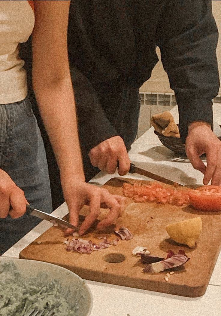 two people are preparing food on a cutting board