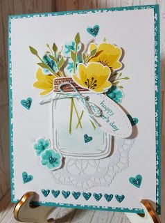 a close up of a card with flowers in a mason jar on a wooden table