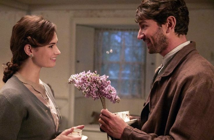 a man and woman standing next to each other with flowers in their hands while holding coffee cups