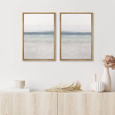 two framed pictures on the wall above a dresser with vases and flowers in front of it