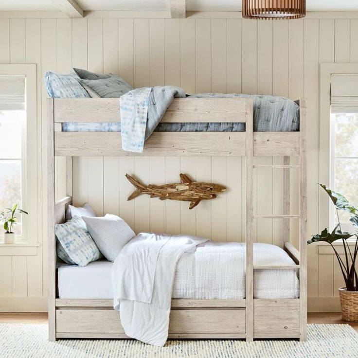 a wooden bunk bed sitting next to a green plant in a room with white walls