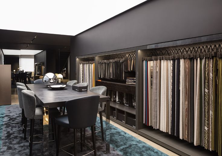 a dining room table surrounded by lots of different colored fabrics on display in a store