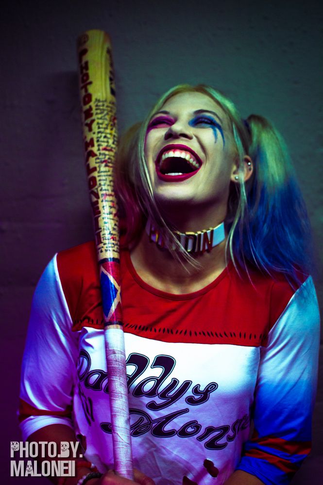 a woman with blue hair and makeup holding a baseball bat in one hand and smiling at the camera