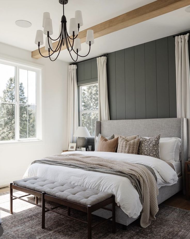 a large bed sitting under a window next to a wooden ceiling fan and two lamps