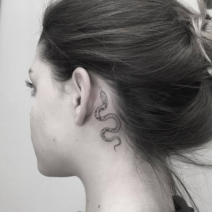 a woman with a snake tattoo on her left side behind her ear, looking to the right