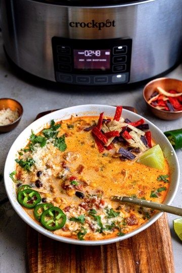 a white bowl filled with mexican food next to an instant pressure cooker on a wooden cutting board