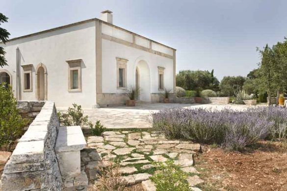 the house is white and has stone steps leading up to it