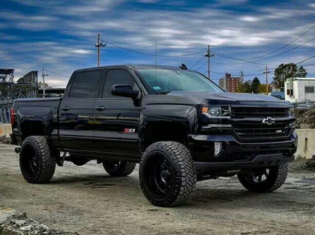 a black truck is parked in the dirt