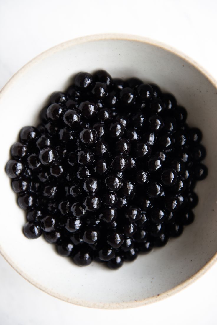 a white bowl filled with blackberries on top of a table