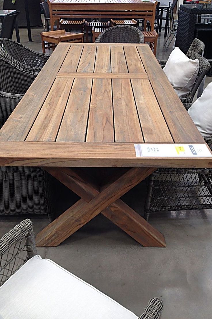 a wooden table sitting on top of a patio next to wicker chairs and tables