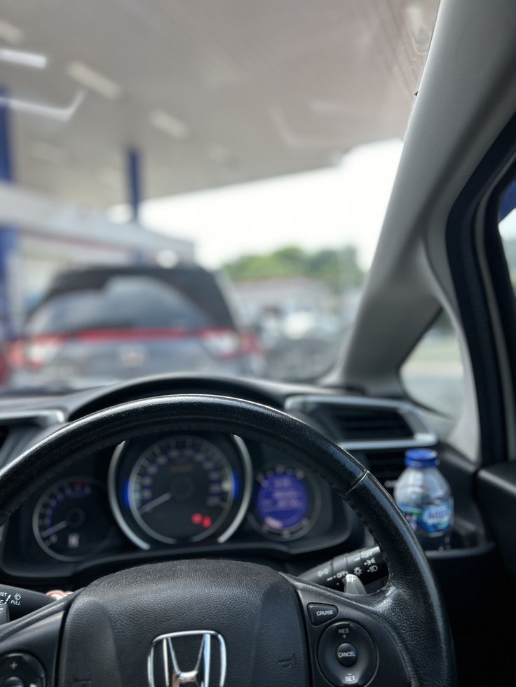 the interior of a car with steering wheel, dashboard and gauges on display at a gas station