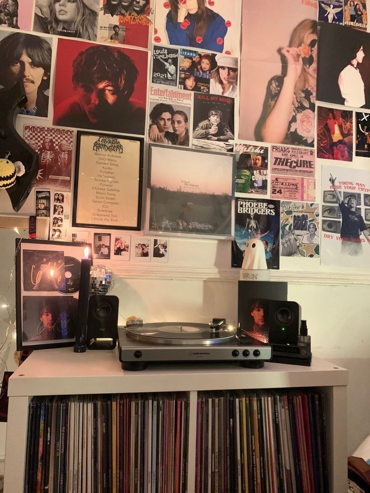 a record player sitting on top of a white shelf in front of a wall covered with records