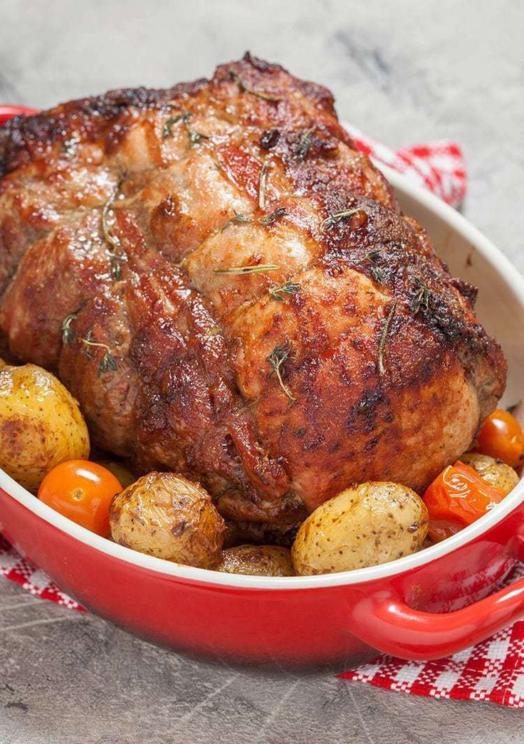 a close up of a meat in a pot with potatoes and tomatoes