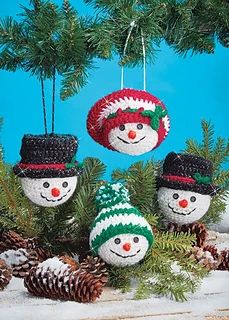 knitted snowman ornaments hanging from a pine tree