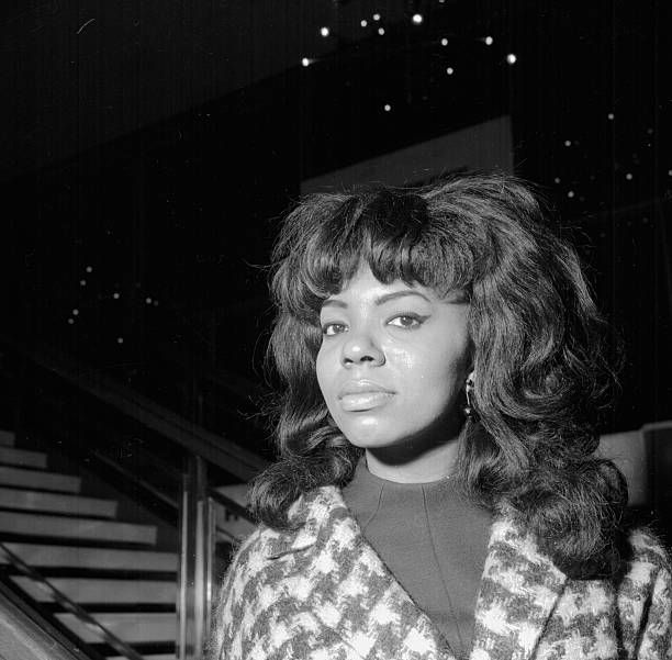 a black and white photo of a woman standing in front of stairs