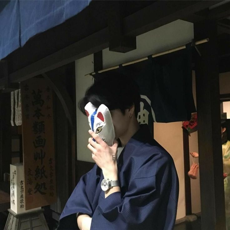 a man in a blue kimono is holding a mask