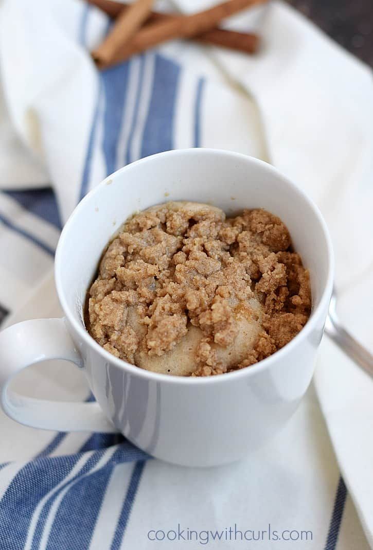 a white bowl filled with food on top of a blue and white table cloth next to cinnamon sticks