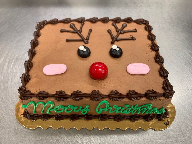 a decorated christmas cake with chocolate frosting and reindeer's noses on it, sitting on a table