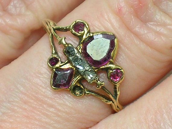 a close up of a person's hand wearing a ring with flowers on it