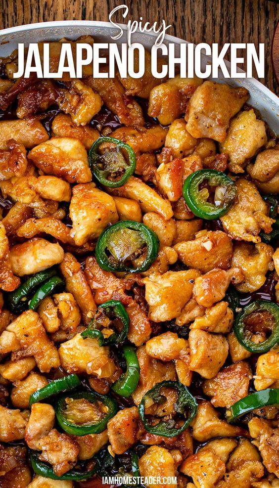 chicken with peppers and jalapenos in a pan on top of a wooden table