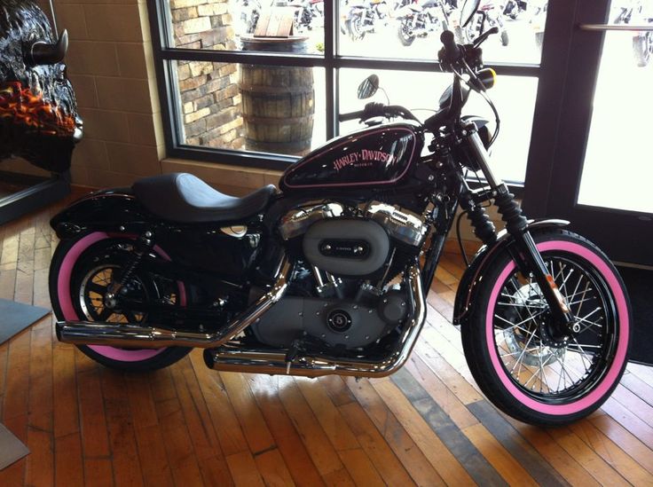 a black and pink motorcycle is parked in front of a window on a wooden floor