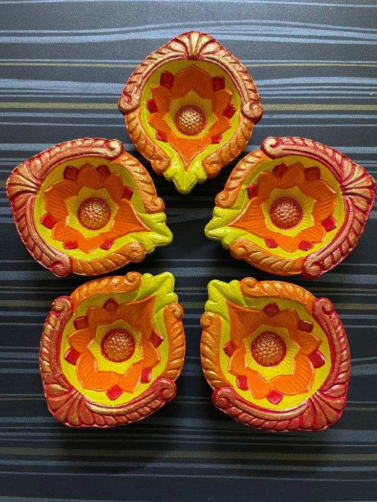 four orange and yellow vases sitting next to each other