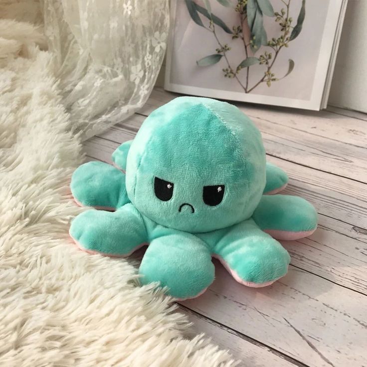 an octopus stuffed animal sitting on top of a white rug next to a framed photo