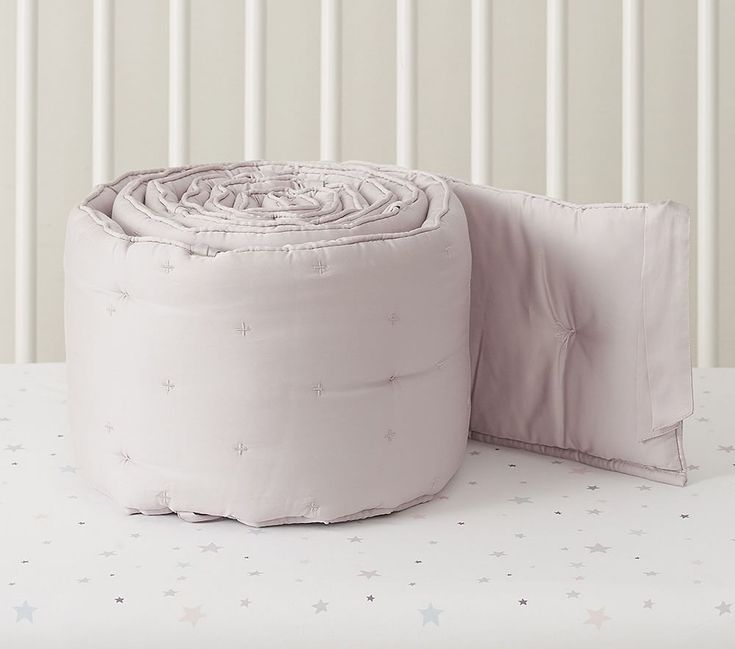 a pink blanket and pillow on top of a white bed with star patterned wallpaper