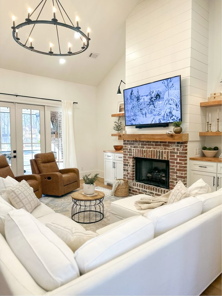 a living room filled with furniture and a flat screen tv mounted on the wall above a fire place