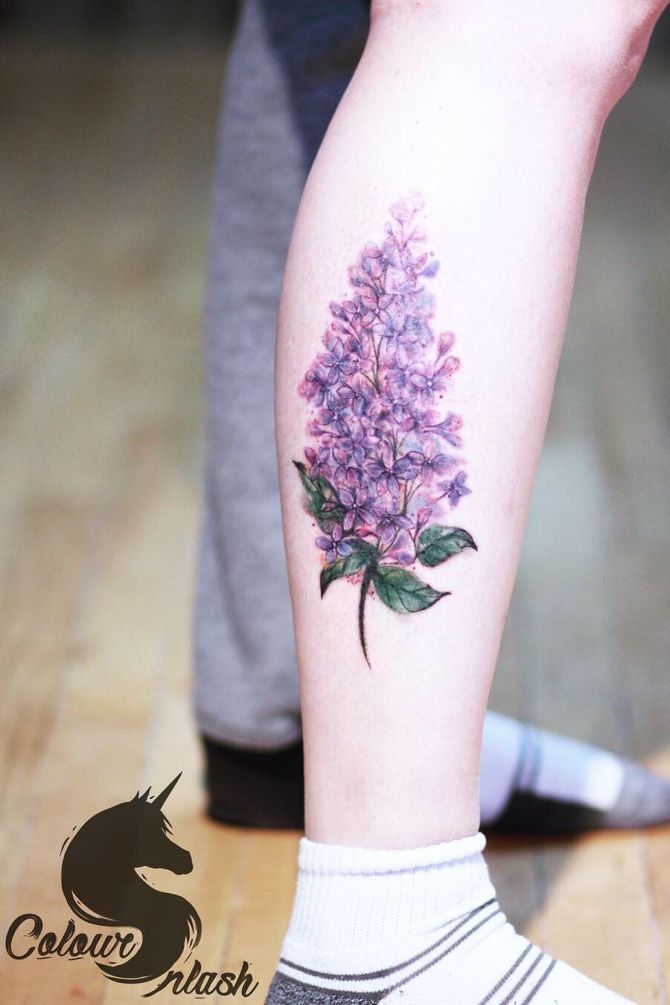 a person with a tattoo on their leg that has purple flowers on it and green leaves