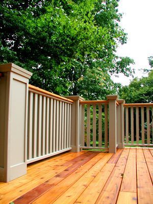 a wooden deck with white railing and trees in the background